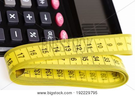Tape for measurement in yellow color with plastic calculator in close up isolated on white background. Diet and calories counting concept
