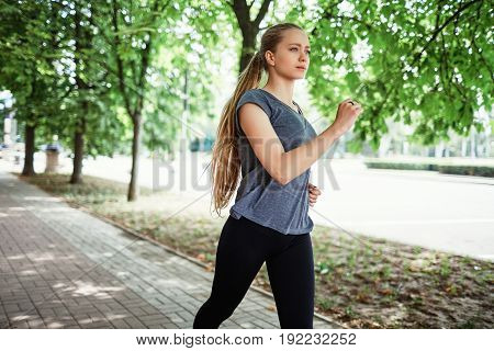 Sports girl doing stretching near building and running down the street in the morning