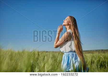 Beautiful happy woman girl smiling outdoors on green wheat field in summer nature. Pretty woman with natural makeup curly hairstyle in country village with green wheat. Attractive beauty girl in park