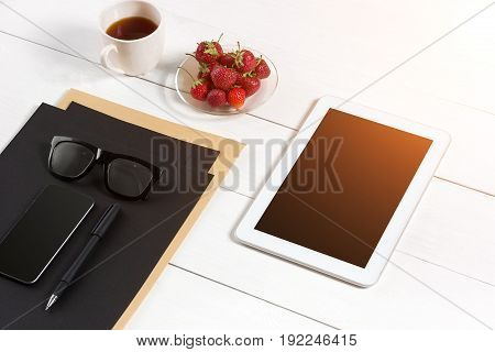 Modern workplace with digital tablet computer and mobile phone, cup of coffee, pen and empty sheet of paper. Top view and copy space for text