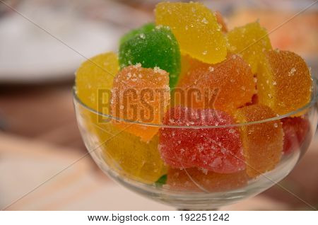 Many colorful marmalades in a glass bowl on a table
