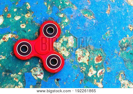 Top view of the popular red spinner gadget in 2017 against the background of the old wall with the overgrown blue paint