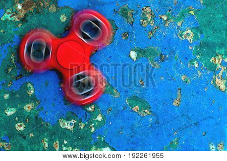 Top view of the popular red spinner gadget in 2017 against the background of the old wall with the overgrown blue paint