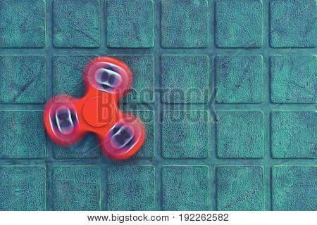 Top view of the popular red spinner gadget in 2017 on the blue-green background. Popular spinner gadget in 2017.