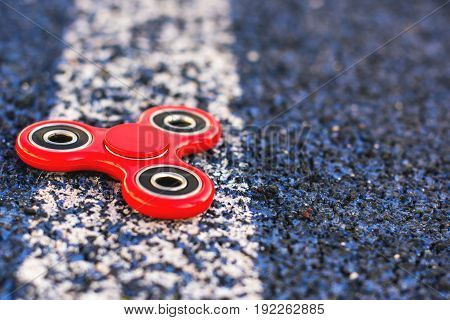 Popular spinner gadget in 2017 on a blue and white background. Modern red plastic spinner fidget game for young people.