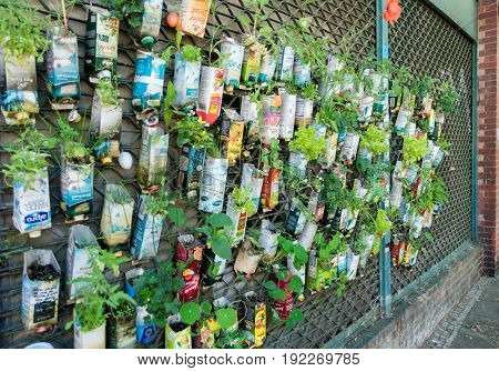BERLIN, GERMANY - June 2, 2017: Old beverage cartons used as plant pots hanging on window grate. Urban guerilla gardening in Berlin City.