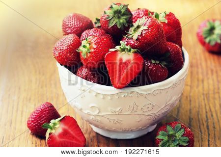 Fresh strawberries in bowl on wood table, organic garden berries .