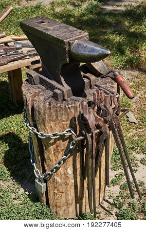 Anvil on a wooden log blacksmith ladle chain and ladle for coal
