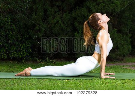 young attractive happy asian woman in white outfit practicing her yoga balance at her home backyard room for text copy space