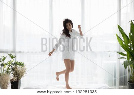 Asian woman Beautiful young smiling and jumps on his bed after waking