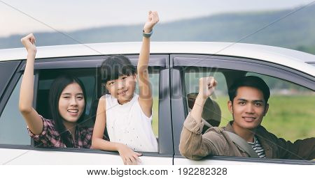 happy little girl with asian family sitting in the car for enjoying road trip and summer vacation
