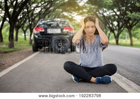 Stressed women sitting after a car breakdown with Red triangle of a car on the road