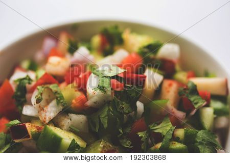 Indian Green Salad also known as Kachumber is a colourful salad dish in Indian cuisine consisting of fresh chopped tomatoes, cucumbers, onions, and sometimes, chili peppers. selective focus