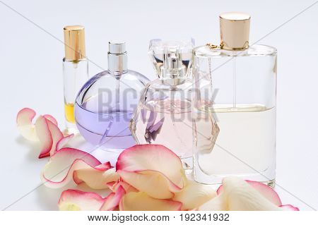 Perfume bottles with flower petals on light background. Perfumery, fragrance collection. Women accessories