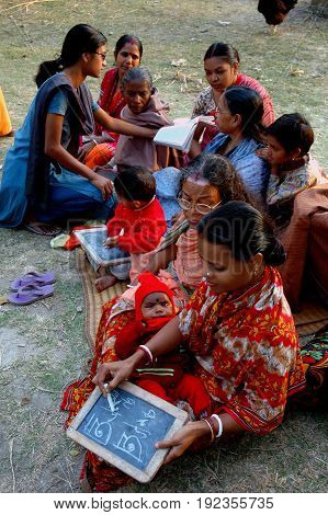 KOLKATA, JANUARY 20, 2007: A young girl is helping an ender woman to understand the alphabets on January 20, 2007 in a rural area near Kolkata, India.