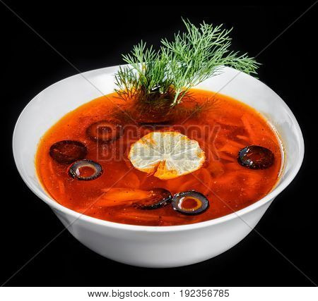 Soup with meat olives herbs and lemon in bowl isolated on black background homemade food. Traditional Russian soup - solyanka