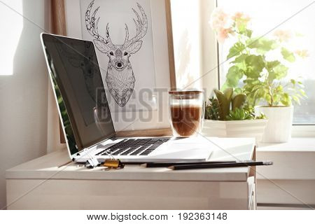 Creative workplace with laptop near windowsill in modern room