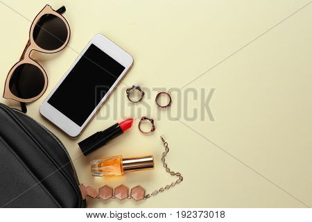 Perfume bottle with cosmetic bag and phone on color background