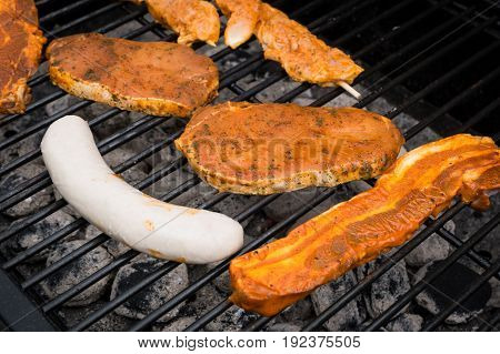 Grilling sausages and fresh steaks on barbecue grill.