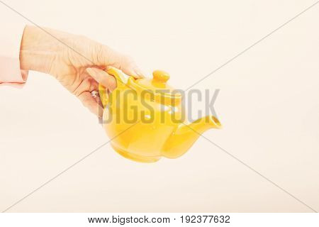 Senior businesswoman's hand holding teakettle over white background