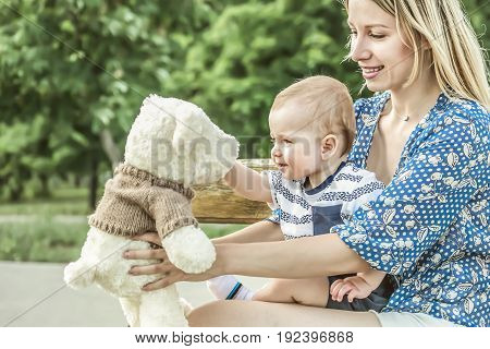 Pretty mather playing with baby boy outdoor on nature at sunny summer say