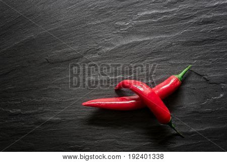 Red chili peppers over dark slate. Food background overhead view.