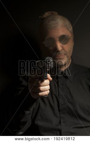 criminal bandit man wearing a stocking mask holds a gun in his hand on black background