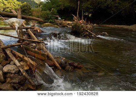 Improvised run-of-stream micro hydro electricity generation. Using boat propellers in rapids driving shafts to electric motors, all supported on bamboo scaffolding. Nam Ou River, Laos