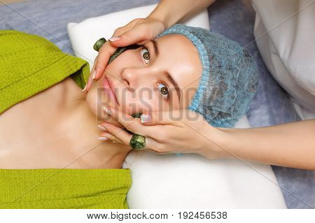 Spa treatment. Facial massage with jade stones. Alternative medicine. Massage of cheek zone. Guasha