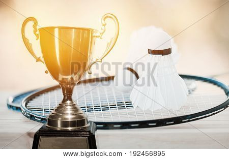 Trophy Award for winner champian shuttlecocks on hand and racket badminton with wood background Awards and winners concept