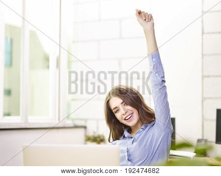 young caucasian business woman raising arm celebrating achievement and success.