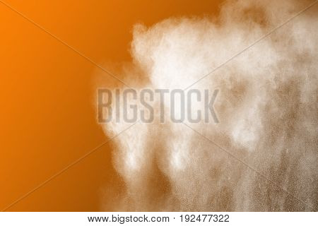 Abstract white powder explosion on orange background.