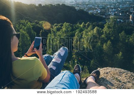 woman with man sitting on the top of the hill injoy view, first person view ma taking picture of th woman