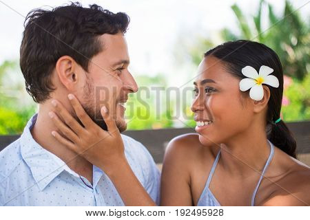 Closeup of smiling young Asian woman embracing boyfriend neck