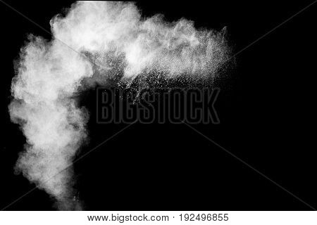 Freeze motion explosion of white dust on black background. By throwing talcum powder out of hand.