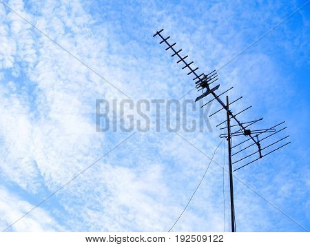 Silhouette TV antenna on cirrocumulus clouds and blue skies
