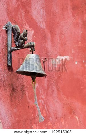 vinage bell with figure squirrel on red wall