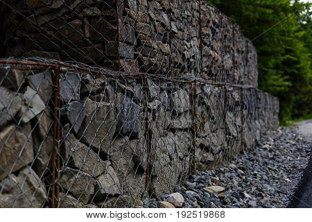 Slope and earth retention wall management with rocks and wire mesh cage system in tropical hilly terrain