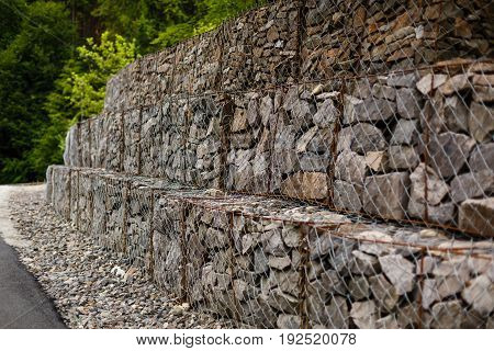 Slope and earth retention wall management with rocks and wire mesh cage system in tropical hilly terrain