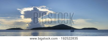 Majestic panoramic seascape with clouds in form of holy resurrection over Luis Pena Cay and calm sea with sailboat on Caribbean Island of Isla Culebra in Puerto Rico