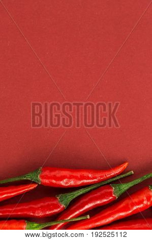 red hot chili peppers, popular spices concept - collage of some beautiful red hot chili pepper pods half filled on red background, top view, flat lay, free space for your text, verical