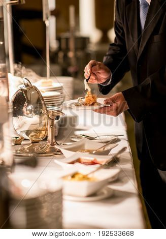 Businessman hands taking food in buffet line indoor in luxury hotel