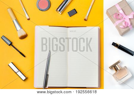 Open notebook with to do list, planning concept. Make up items, perfume and gift box on pastel background, top view, flat lay, copy space