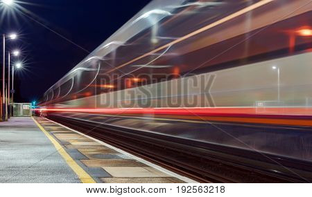 Speeding train through a UK station at night