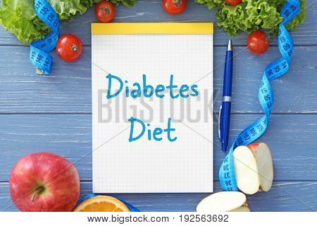 Notebook with text DIABETES DIET and healthy food on wooden background. Health care concept