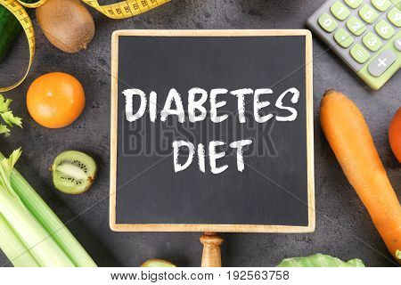 Small chalkboard with text DIABETES DIET and healthy food on gray background. Health care concept