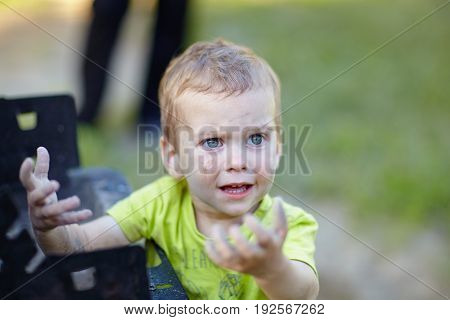 Little boy smeared his hands in the ashes and was surprised.
