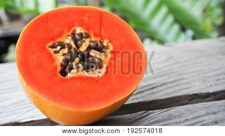A half of freshly yellow orange papaya on wood table in garden background