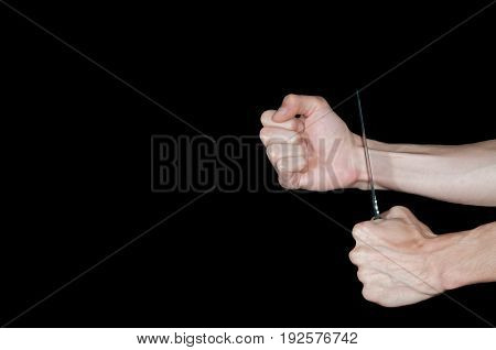 Suicide. Man want to commit suicide by cutting his veins with knife. Low key image, isolated on black background.