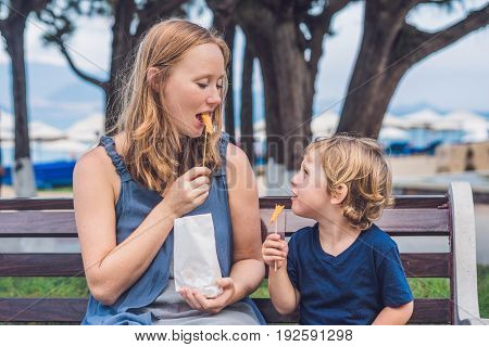 Mom And Son Eat Fried Sweet Potatoes In The Park. Junk Food Concept